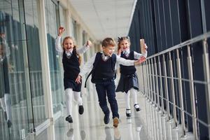 escolares activos en uniforme corriendo juntos en el corredor. concepción de la educación foto