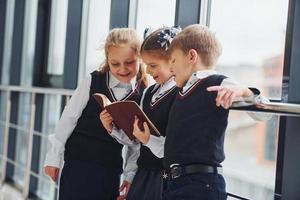 niños de la escuela en uniforme leyendo libros juntos en el pasillo. concepción de la educación foto