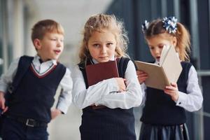 School kids in uniform together with books in corridor. Conception of education photo