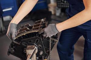 Close up view of professional repairman in garage that works with broken automobile engine photo