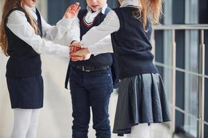 School kids in uniform making victory gesture together in corridor. Conception of education photo