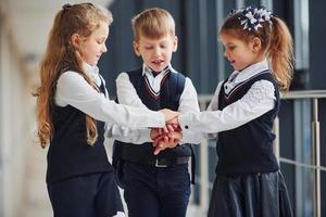 School kids in uniform making victory gesture together in corridor. Conception of education photo