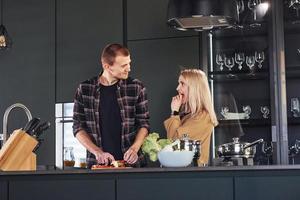 Young couple in casual clothes standing together in kitchen and preparing food photo