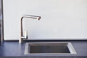 Silver colored tap indoors in the kitchen at daytime. Conception of modern decor photo