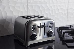 Close up view of silver colored toaster that standing on gas stove indoors in kitchen photo