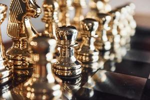 Chess board with metal figures on it indoors on the table at daytime photo