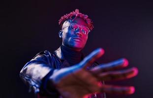 Having fun. Futuristic neon lighting. Young african american man in the studio photo