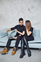 Man with curly hair and woman that in black clothes sitting with laptop indoors have a work photo