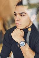 Portrait of confident young man in black sweater that sitting indoors photo