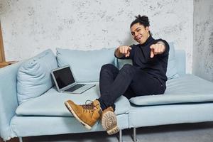 Handsome young man with curly black hair indoors with laptop have fun photo