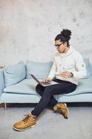 Handsome young man with curly black hair and cup of drink indoors with laptop photo