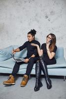 Man with curly hair and woman that in black clothes sitting with laptop indoors photo