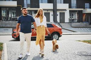 Lovely couple have a walk together with dog outdoors near the car photo