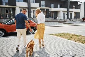 Lovely couple have a walk together with dog outdoors near the car photo