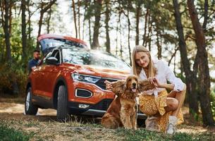 Couple with dog have weekend outdoors in the forest with car photo