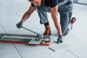 Man in grey uniform installing plate indoors in modern big office at daytime photo