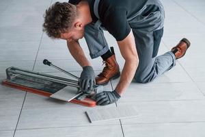 Man in grey uniform installing plate indoors in modern big office at daytime photo