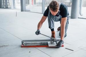 Man in grey uniform installing plate indoors in modern big office at daytime photo