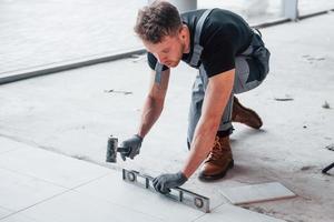 Man in grey uniform installing plate indoors in modern big office at daytime photo