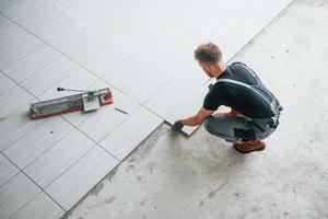 Top view of man in grey uniform that installing plate indoors in modern big office at daytime photo