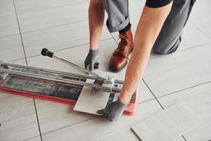 Man in grey uniform installing plate indoors in modern big office at daytime photo