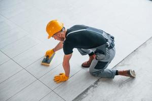 Top view of man in grey uniform that installing plate indoors in modern big office at daytime photo