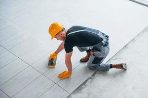 Top view of man in grey uniform that installing plate indoors in modern big office at daytime photo