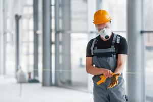 Man in grey uniform preparing for work indoors in modern big office at daytime photo