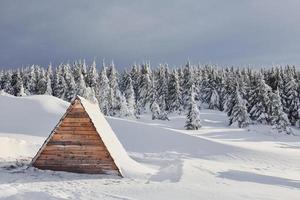 parte del edificio de madera en el suelo. mágico paisaje invernal con árboles cubiertos de nieve durante el día foto