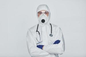 Male doctor scientist in lab coat, defensive eyewear and mask standing against white background photo