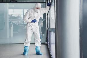 Male doctor scientist in lab coat, defensive eyewear and mask feels bad, exhausted and sick photo