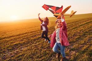 dos amigas se divierten juntas con cometas y aviones de juguete en el campo durante el día soleado foto