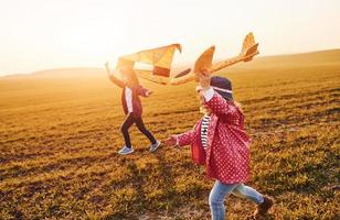 Two little girls friends have fun together with kite and toy plane on the field at sunny daytime photo