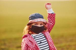 retrato de una linda niña con una máscara protectora negra que está al aire libre foto