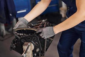 Close up view of professional repairman in garage that works with broken automobile engine photo