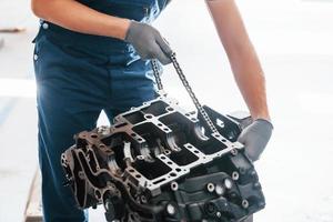 Professional repairman works with broken automobile engine photo