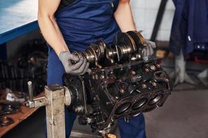 Professional repairman in garage works with broken automobile engine photo