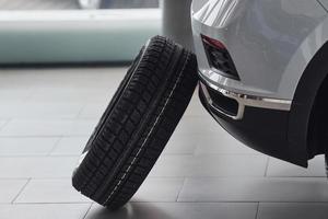 Close up view of tyre that leaning on front of the white car indoors photo