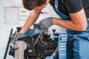 Close up view of professional repairman in garage that works with broken automobile engine photo