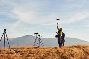 Male photographers standing and working at majestic landscape of autumn trees and mountains by the horizon photo