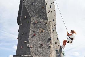Little girl in casual white clothes training rock climbing outdoors photo
