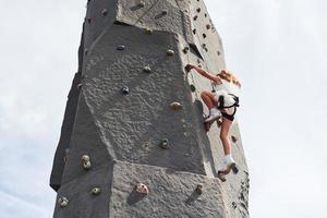 Little girl in casual white clothes training rock climbing outdoors photo