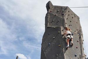 Little girl in casual white clothes training rock climbing outdoors photo