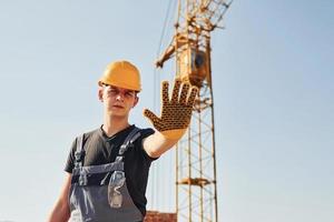 muestra la señal de stop a mano. trabajador de la construcción en uniforme y equipo de seguridad tiene trabajo en la construcción foto