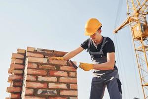 Installing brick wall. Construction worker in uniform and safety equipment have job on building photo