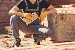 Construction worker in uniform and safety equipment sits and have job on building photo