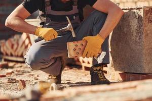 Construction worker in uniform and safety equipment sits and have job on building photo