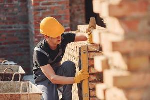 Measures of brick wall. Construction worker in uniform and safety equipment have job on building photo