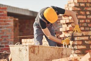 Busy with brick wall. Construction worker in uniform and safety equipment have job on building photo