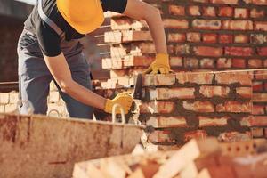 Busy with brick wall. Construction worker in uniform and safety equipment have job on building photo